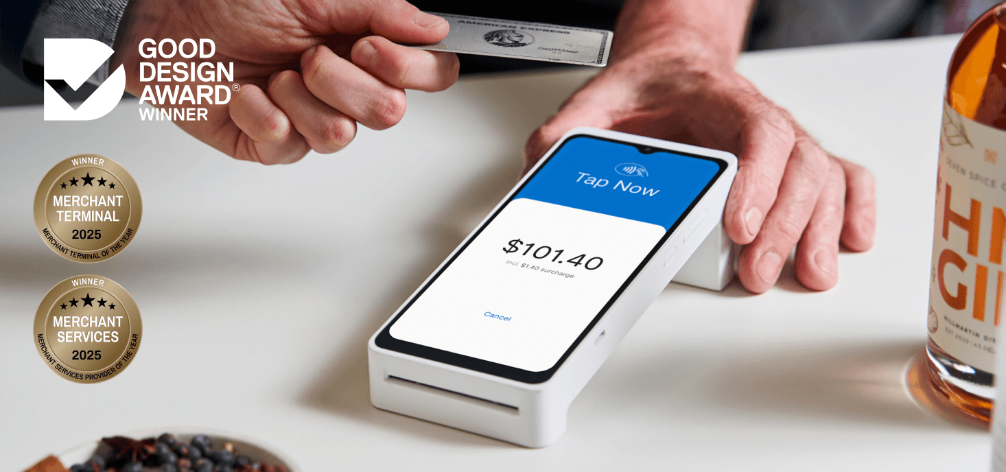 Person making a payment with a card on a smartphone terminal displaying $101.40. "Good Design Award" logo and a bottle are visible nearby.
