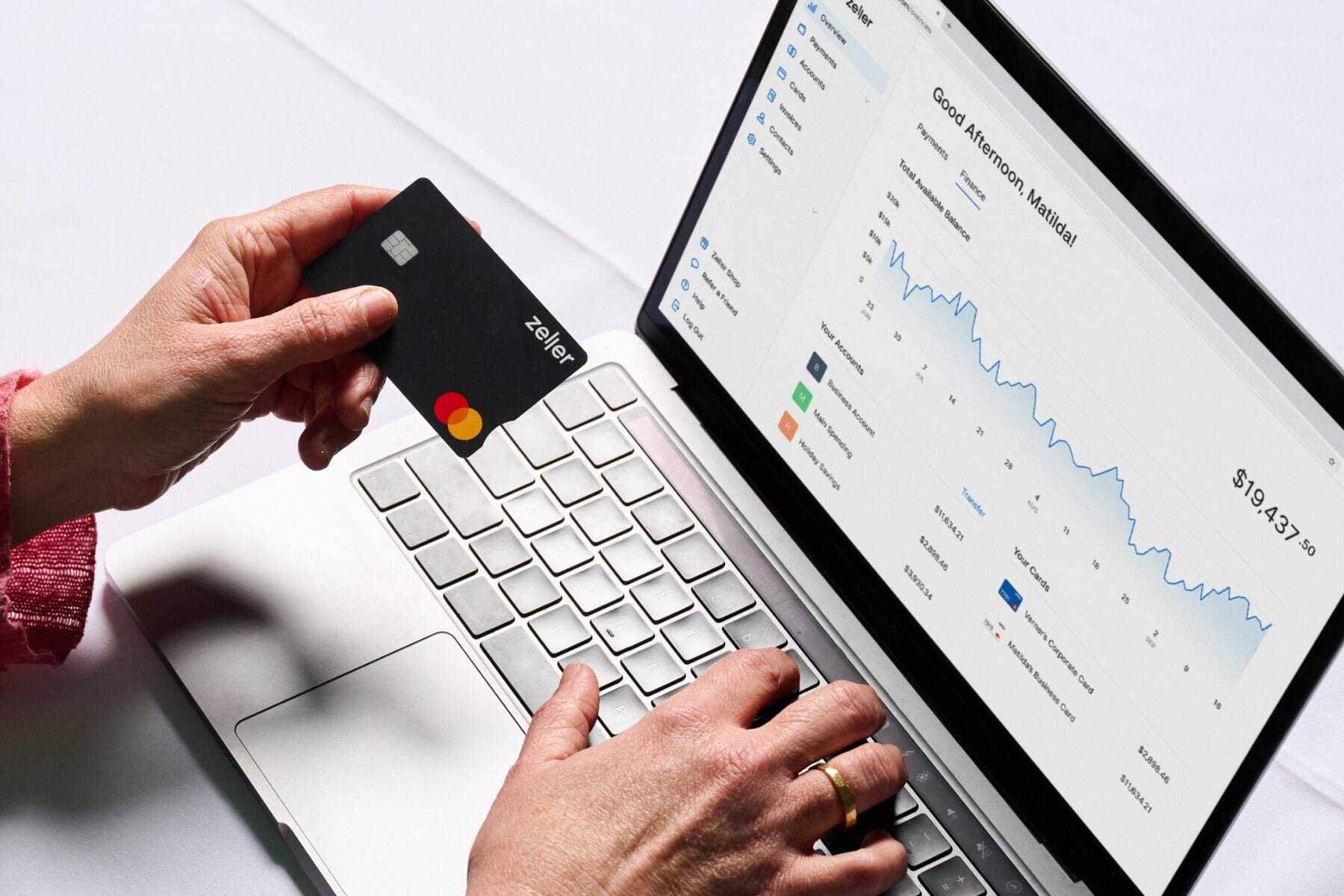 Black Business Debit Card with view of the Zeller Dashboard on a laptop